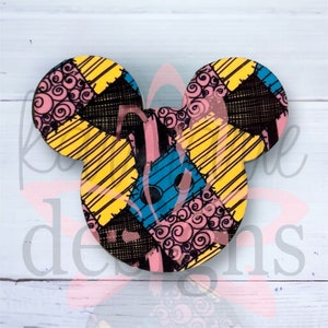 Peut inclure: Une découpe en forme de tête de Mickey Mouse présentant un motif patchwork de textures de tissu jaune, bleu clair, rose avec des tourbillons noirs et noir hachuré. Le design se compose de diverses formes géométriques assemblées en un motif coloré.