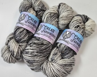 May include: Three skeins of black and white yarn with a speckled pattern. Each skein has a label that reads "Create Yarnworks" with contact information.