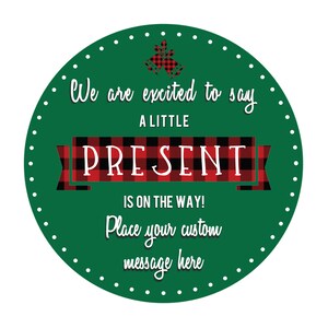 Pu&ograve; includere: Un cerchio verde con punti bianchi attorno al bordo. Il testo "We are excited to say A LITTLE PRESENT IS ON THE WAY!" &egrave; scritto in bianco. Un nastro a quadri rossi e neri con un fiocco bianco &egrave; sopra il testo "PRESENT".
