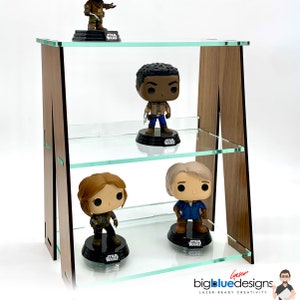Może przedstawiać: Trójpoziomowa drewniana półka ze szklanymi półkami, na której wystawione są cztery figurki Star Wars Pop!. Półka wykonana jest z drewna z wykończeniem orzechowym i ma przezroczysty szklany blat.