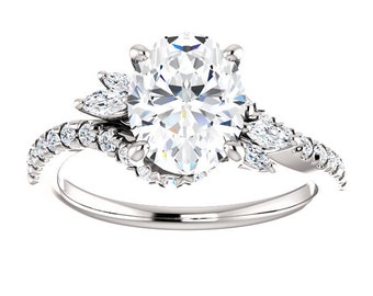 May include: A silver engagement ring featuring a large oval-shaped centre stone and smaller pear-shaped stones on the band. The band is set with smaller round stones.