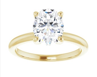May include: A gold solitaire engagement ring with an oval-shaped diamond.