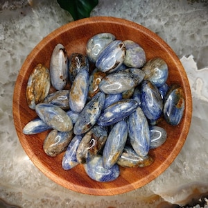 May include: A bowl of blue and brown tumbled stones. The stones are smooth and polished, and they have a variety of shapes and sizes.