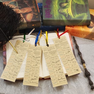 May include: A collection of Harry Potter books with themed bookmarks and a wand. The bookmarks are designed to look like library cards, with colorful ribbons attached. A black feather quill is also present.