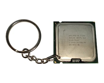 May include: A silver-colored keychain with a metal ring and chain attached to a computer processor. The processor is square with a green border and has text that reads "INTEL CORE 2 DUO".