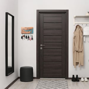 Full entryway scene with a custom map key holder mounted on the wall near a dark wood door, mirror, bench, and coat rack. The piece reads as functional minimalist wall decor designed for organized modern living.