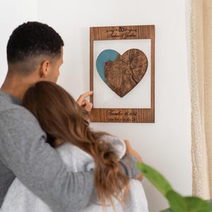 May include: A wooden heart-shaped map with a blue and brown color scheme. The map is framed in a dark wood frame and includes the text "Andrew & Jocelyn" and "November 16, 2023,  Coroner Park in La Jolla, CA".