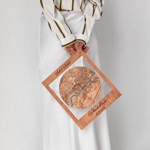 May include: A square wooden frame featuring a circular laser-engraved map with a blue river detail. The frame is inscribed with the text Scott & Michele and Where it all began 10-21-2023. The wood has a natural light brown finish.