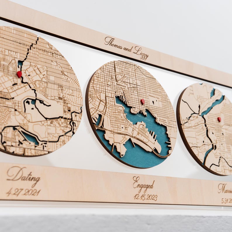 May include: A wooden wall display featuring three circular laser-cut maps with teal water details and red location pins. The top horizontal bar is engraved with "Thomas and Lizzy," while the bottom bar displays "Dating 4.27.2021," "Engaged 12.15.2023," and "Married 5.31.2024."