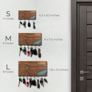 A light wood custom map key holder is displayed on a bright entryway wall near a door and dried greenery. The piece works as modern wall storage that keeps daily keys visible and easy to grab.