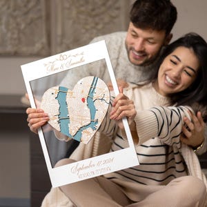 May include: A white wooden frame with a heart-shaped map inside. The map is of New York City and has a red pin marking a location. The frame has the text "Marco & Samantha" and "September 17, 2021 40.4545&deg;N 73.9758&deg;W" written on it.