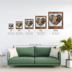 Size chart for the personalized wooden heart map wall art, showing the design in several dimensions from small to extra large above a sofa. This image helps buyers compare scale before choosing the best size for their home or gift occasion.