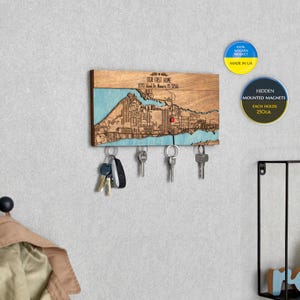 May include: Wooden key holder with a map of a city and the text "OUR FIRST HOME 8370 Bland Dr. Mar 32566". The key holder has five hooks and is made in Ukraine. The key holder has hidden magnets that can hold up to 250 grams each.