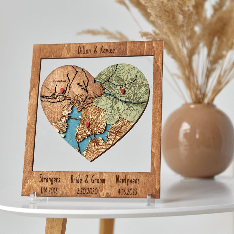 Personalized puzzle map wall art in a rustic wood frame, layered heart-shaped maps with red pins, custom couple names and milestone dates—5th wedding anniversary gift for couple