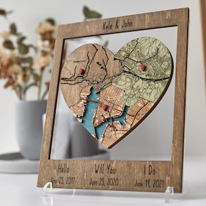 Angled close-up of a dark wood framed heart puzzle map on an acrylic stand, showing the three connected map sections and milestone captions below. This photo highlights the dimensional craft detail and romantic storytelling design of the keepsake.