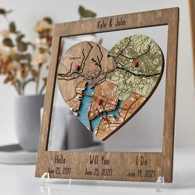 Angled close-up of a dark wood framed heart puzzle map on an acrylic stand, showing the three connected map sections and milestone captions below. This photo highlights the dimensional craft detail and romantic storytelling design of the keepsake.