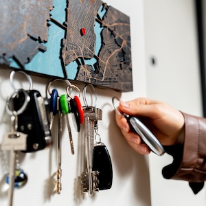Close-up of a dark wooden magnetic key organizer with keys held neatly below the personalized map. This image shows how the hidden magnets keep everyday keys organized near the entryway.