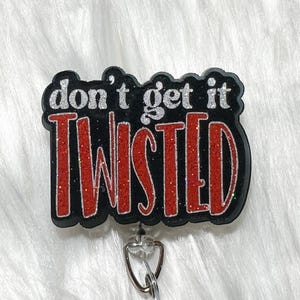 May include: A black badge reel with the phrase "don't get it TWISTED" in silver and red glitter lettering. The badge reel has a silver metal clip and a clear plastic retractable cord.