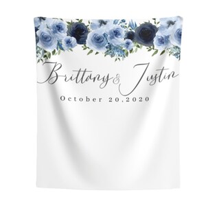 Pu&ograve; includere: Uno sfondo bianco con una ghirlanda di fiori blu in alto. Il testo "Brittany & Justin" &egrave; scritto in corsivo sotto la ghirlanda, seguito dalla data "October 20, 2020".