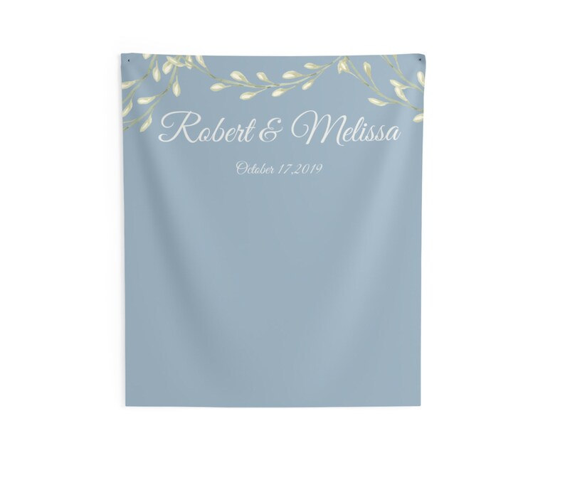 Puede incluir: Un tel&oacute;n de fondo azul claro con una guirnalda floral blanca en la parte superior. El texto "Robert & Melissa" est&aacute; escrito en blanco en cursiva, con la fecha "October 17, 2019" escrita debajo en una fuente m&aacute;s peque&ntilde;a.