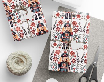 May include: Gift wrap featuring a repeating pattern of nutcracker figurines and red flowers on a white background. The wrapping paper is tied with twine and a small white tag.