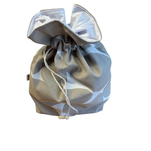 May include: A gray drawstring bag with a white pattern of abstract shapes. The bag is made of fabric and has a white lining.