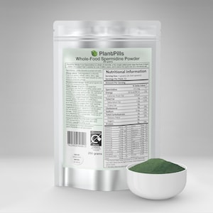 以下が含まれることがあります： 白い袋に入ったPlantPills Whole-Food Spermidine Powder、緑藻の栄養補助食品。栄養成分表示と白いボウルに入った緑色の粉末スプーン付き。袋は250グラムです。