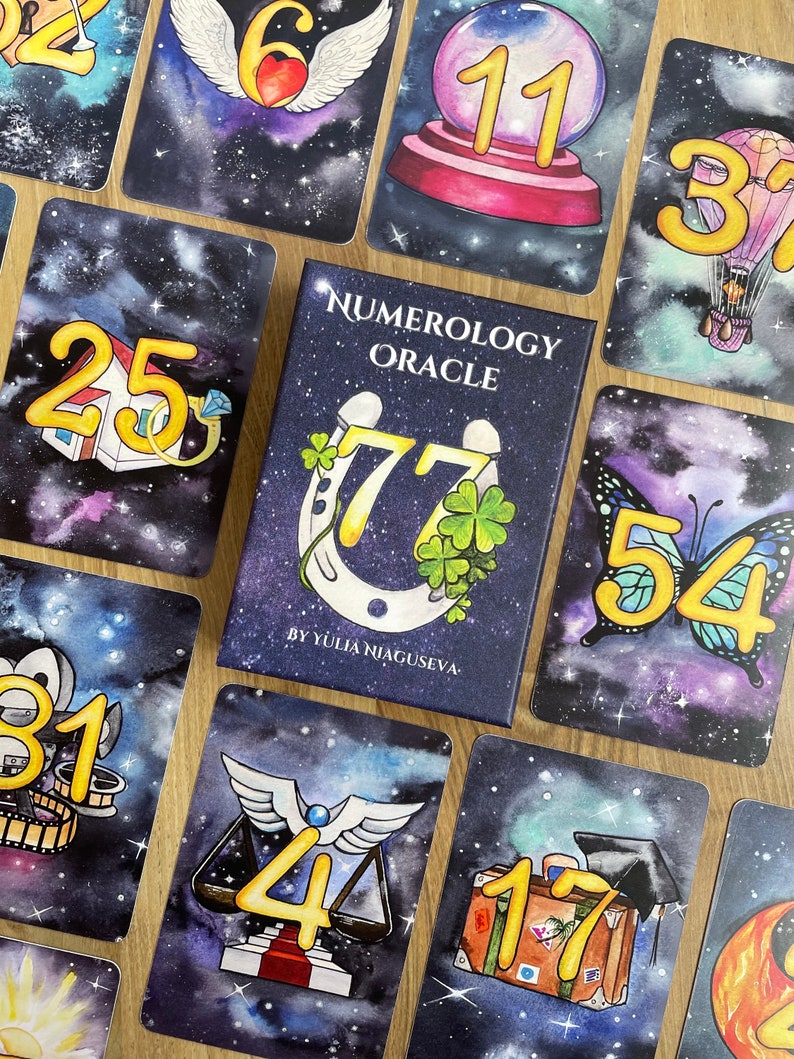 May include: A set of colorful oracle cards with a galaxy background. Each card features a number and an illustration. The cards are part of a numerology oracle deck. The box for the deck is blue with gold lettering and features a horseshoe with four-leaf clovers.