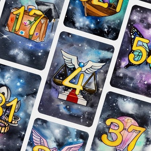 May include: A set of 10 cards with a galaxy background and gold numbers. Each card features a different illustration, including an anchor, a suitcase, a butterfly, a scale, a film reel, a hot air balloon, and a lotus flower.