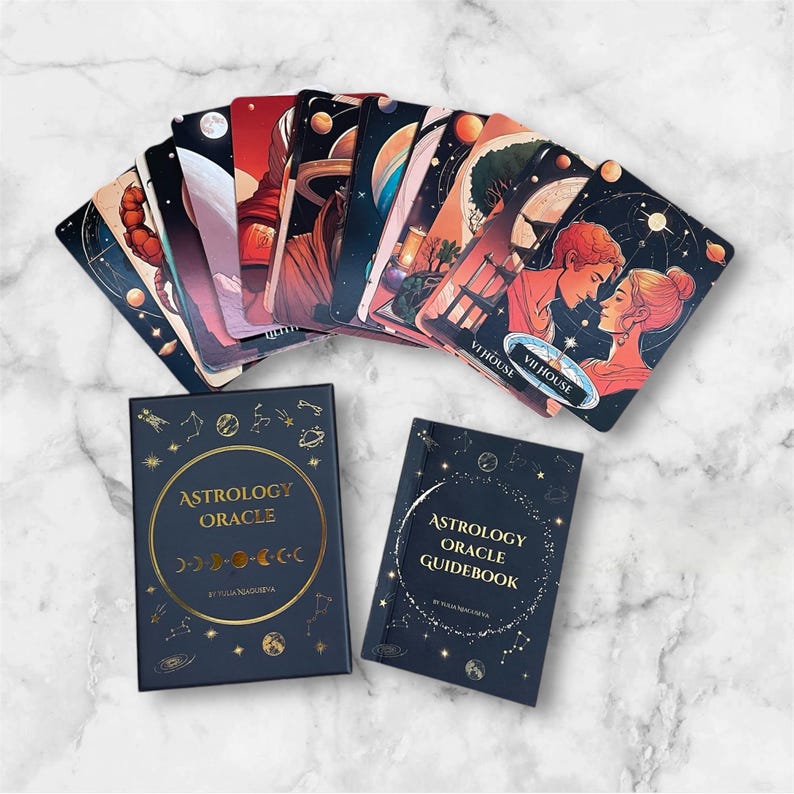 K&ouml;nnte beinhalten: Eine schwarze Box mit goldenen Lettern, auf der "Astrology Oracle" steht, und ein kleineres schwarzes Buch mit goldenen Lettern, auf dem "Astrology Oracle Guidebook" steht. Die Box enth&auml;lt ein Kartenspiel mit Illustrationen von Planeten, Sternen und Himmelsk&ouml;rpern.