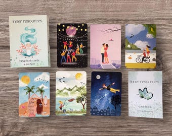 May include: A deck of "Inner Resources" metaphoric cards and a guidebook. The cards feature colourful illustrations of people, nature, and scenes. The card illustrations include a couple kissing, people dancing, and a person flying through the night sky.