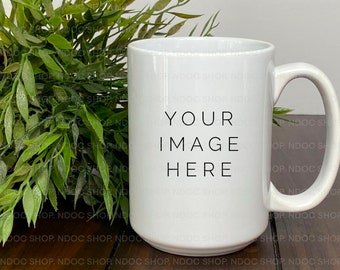 May include: White ceramic mug with a black text overlay that says "YOUR IMAGE HERE". The mug is sitting on a wooden surface next to a potted green plant.