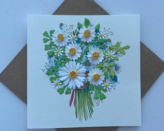 May include: A square greeting card featuring a three-dimensional quilled paper daisy bouquet. The design includes white petals with yellow centers, green paper leaves, and painted blue floral accents on a white background, paired with a brown envelope.
