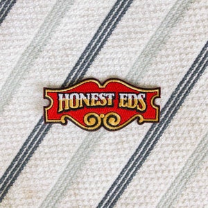May include: Red and gold embroidered patch with the text "Honest Eds" in white lettering.