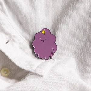May include: Purple cartoon character with a yellow star on its head, resembling a cloud with a grumpy expression. The character is a pin, a popular collectible item.