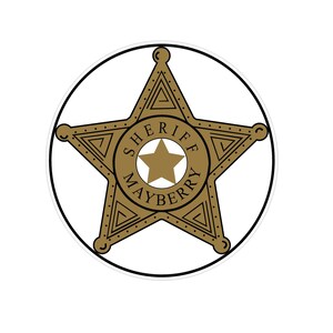 Puede incluir: Una placa de sheriff dorada con un dise&ntilde;o de estrella de cinco puntas. La placa est&aacute; rodeada por un contorno negro y presenta las palabras "SHERIFF MAYBERRY" en un patr&oacute;n circular alrededor de una estrella m&aacute;s peque&ntilde;a en el centro.
