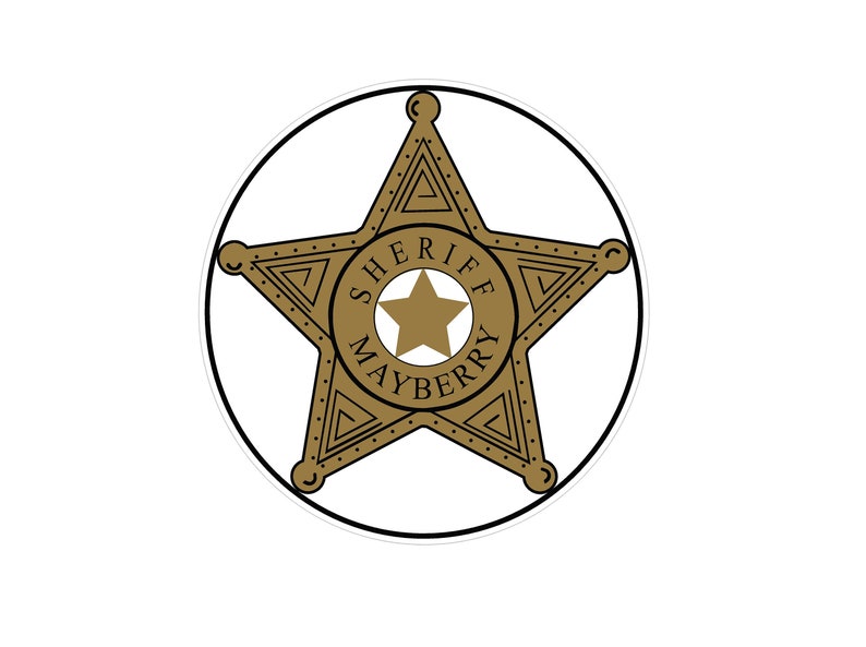 Puede incluir: Una placa de sheriff dorada con un dise&ntilde;o de estrella de cinco puntas. La placa est&aacute; rodeada por un contorno negro y presenta las palabras "SHERIFF MAYBERRY" en un patr&oacute;n circular alrededor de una estrella m&aacute;s peque&ntilde;a en el centro.