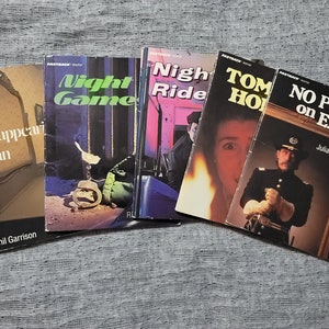 Może przedstawiać: Pięć książek w miękkiej oprawie z różnymi tytułami i autorami. Tytuły to "The Disappearing Man", "Night Game", "Night Ride", "Tom Horn" i "No Power on Earth".