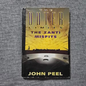 May include: A paperback book cover with a yellow and orange sunset background. The title is "The Outer Limits: The Zanti Misfits" by John Peel.