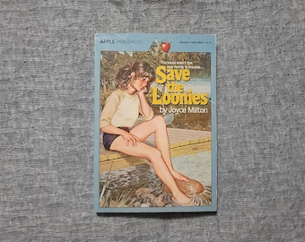 Könnte beinhalten: Ein blaues und weißes Taschenbuch mit einem Bild eines Mädchens, das auf einem Steg sitzt. Der Buchtitel lautet "Save the Loonies" von Joyce Milton.