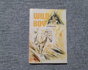 May include: A vintage paperback book cover with a white horse running through a desert landscape. The title is "WILD BOY" by Thomas Fall.
