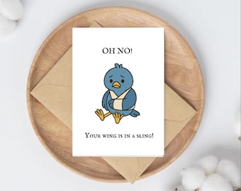 May include: A greeting card featuring a cartoon bird with a wing in a sling, with the text "OH NO! Your wing is in a sling!" The card rests on a wooden plate with a brown envelope.