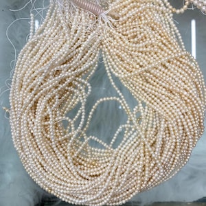 Pode incluir: Um grande fio de pérolas de água doce brancas, perfeito para fazer joias. As pérolas são pequenas e uniformes em tamanho, com um acabamento liso e brilhante.