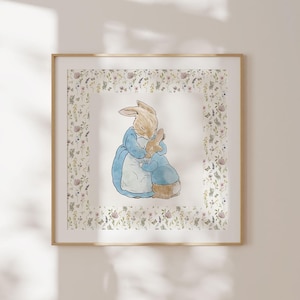 May include: A framed print of a watercolor illustration of two rabbits hugging. The rabbits are surrounded by a border of small flowers and leaves. The background is white.