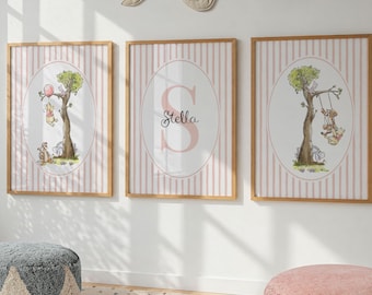May include: Three framed art prints with a light pink striped background and a wooden frame. Each print features a whimsical illustration of a tree with a bunny. One print has the name "Stella".