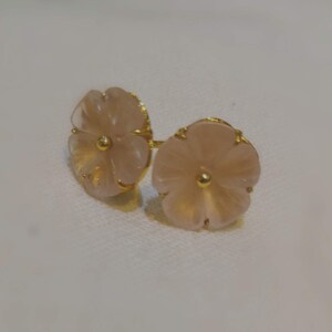 May include: A pair of gold flower-shaped earrings with pink quartz stones.