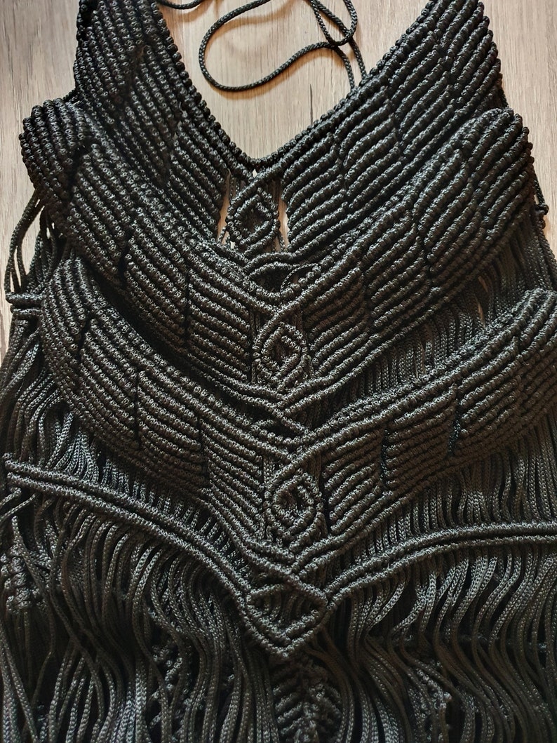 Puede incluir: Top negro de macram&eacute; con un patr&oacute;n geom&eacute;trico y detalles de flecos.