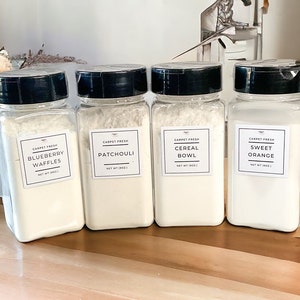 May include: Four clear glass jars with black lids and white labels. The labels have the text "Carpet Fresh" and different scents: Blueberry Waffles, Patchouli, Cereal Bowl, and Sweet Orange.