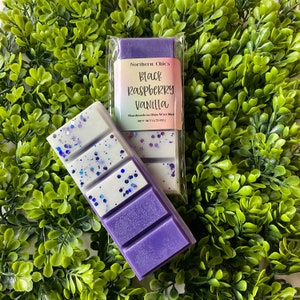 May include: Purple wax melt with white and silver glitter. The wax melt is labeled "Black Raspberry Vanilla" and "Northern Chic's Handmade in Ohio Wax Melts, Net Wt 1.75 oz."