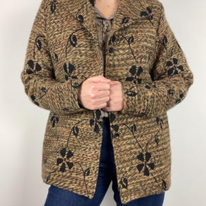 May include: A brown and black patterned blazer with black floral designs. The blazer has a collared neckline and button closure. The jacket is made of a textured fabric.